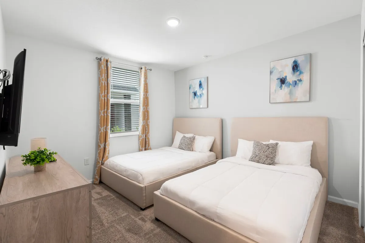 A comfortable second bedroom with two full-size beds, decorative wall art, wooden dresser, and curtains offering privacy and a sense of coziness.