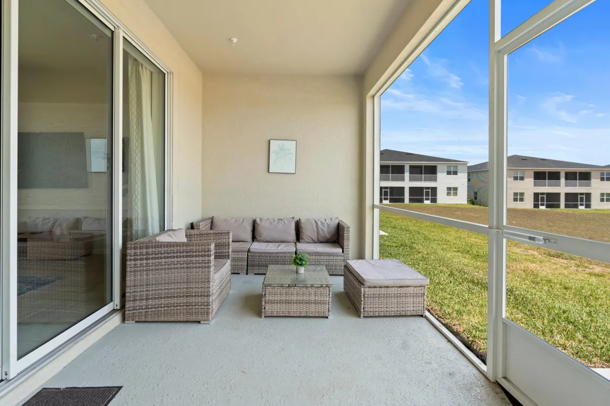 A tranquil patio scene with wicker furniture set on green grass under a clear sky, inviting guests to enjoy morning coffee, socializing, or quiet moments together.
