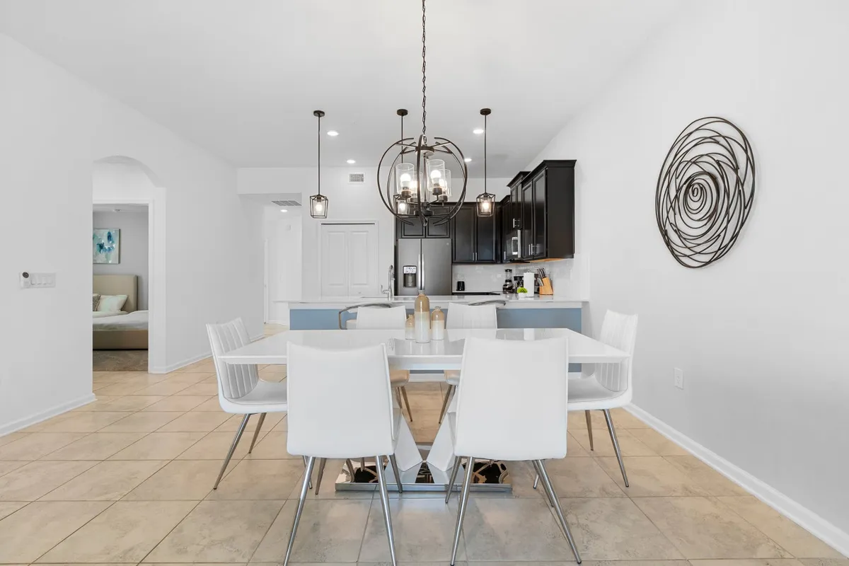 A modern dining table occupies the foreground, illuminated by a stylish light fixture, with the kitchen cabinetry and decorative wall art in the background. This setup invites shared meals and social gatherings, echoing the section's focus on memorable family dining experiences.