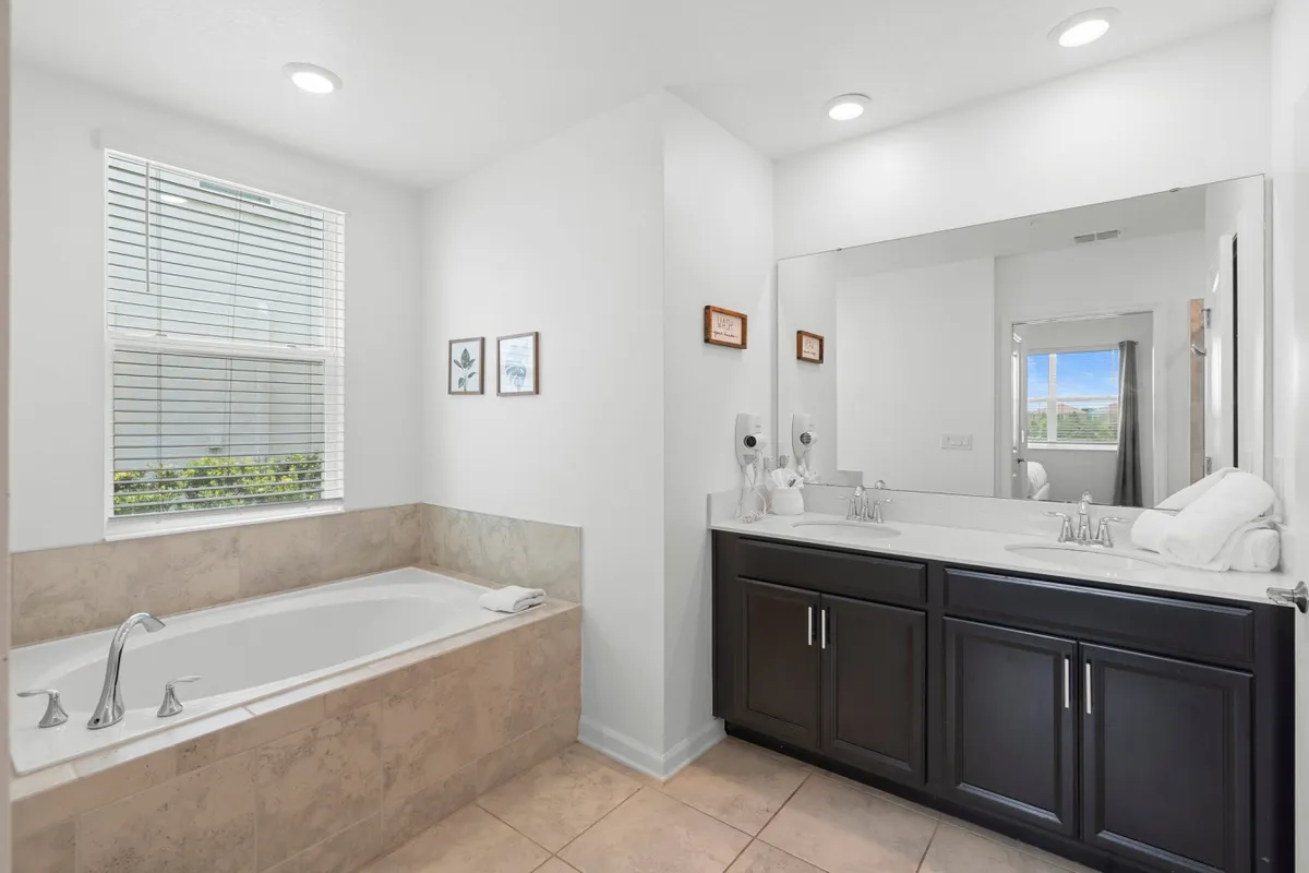 A tranquil bathroom scene with a bathtub, mirror, sink, and framed artwork creating a spa-like atmosphere for relaxation and self-care.