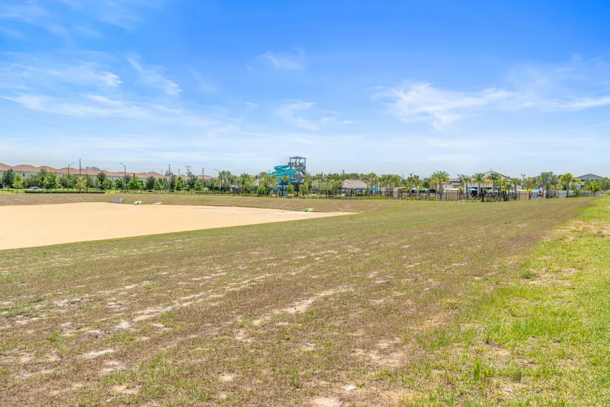 An energetic outdoor recreation area with a water slide, open grassy field, and a play zone, perfect for group activities and fun in the sun. The space is lively and playful, inviting guests to engage in active pursuits together.