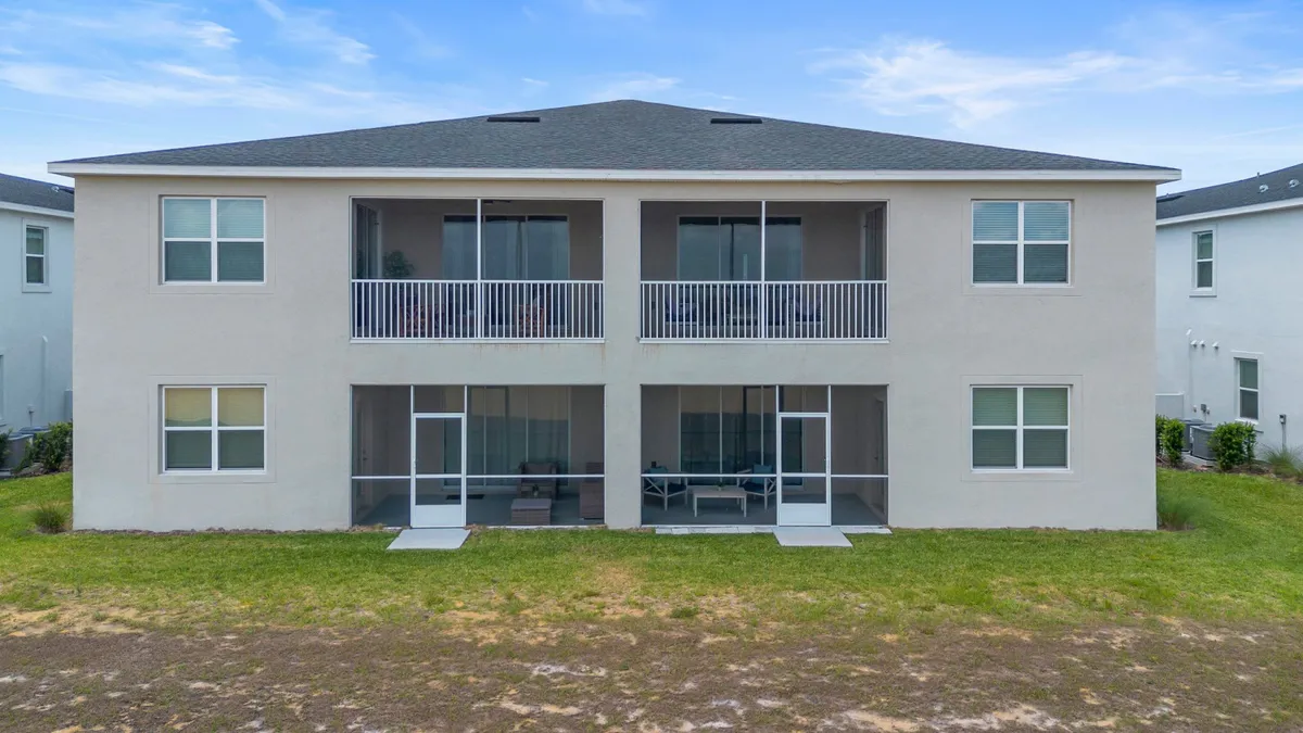 A spacious exterior featuring large balconies, expansive windows, and a green lawn, suggesting plentiful communal space for gatherings and relaxation. The scene conveys opportunities for both indoor-outdoor living and large group get-togethers.